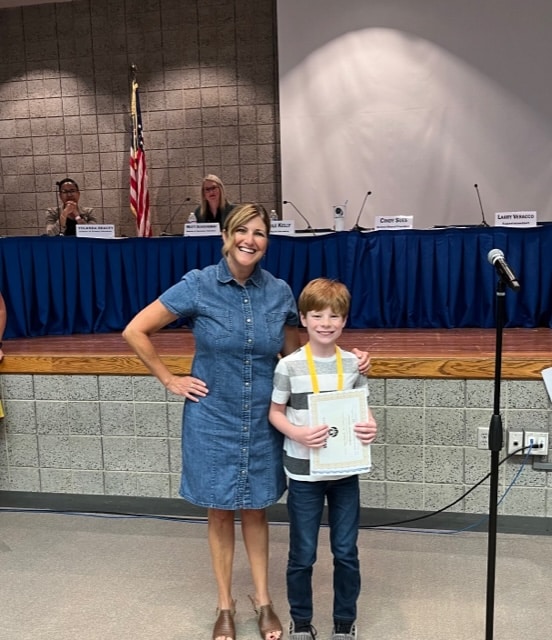 Mrs. Patrick from Protsman congratulates student Dylan Hayward for receiving a perfect score this year on the Wordmasters Challenge.